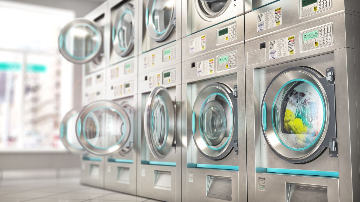 A Row Of Stainless Steel Washing Machines In A Laundromat